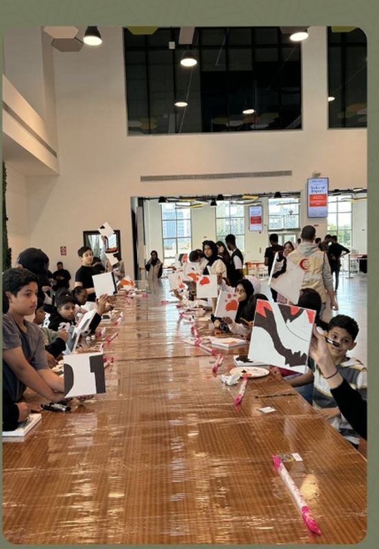 Thirty children painting panels along a long table